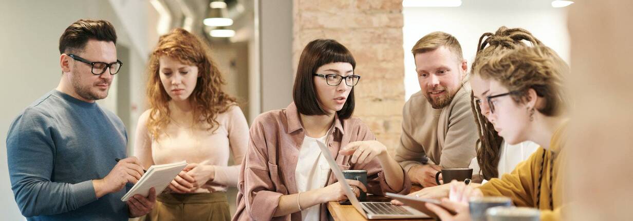 Ein Team ist konzentriert am Arbeiten mit MacBook.