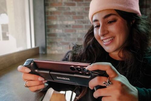 iPhone 15 ist ideal für Mobile Gaming Eine junge Frau mit Beenie spielt auf dem iPhone ein Game