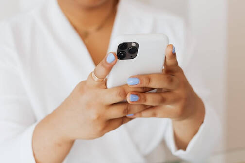 Frau mit blauen Fingernägeln beim Gaming auf dem iPhone