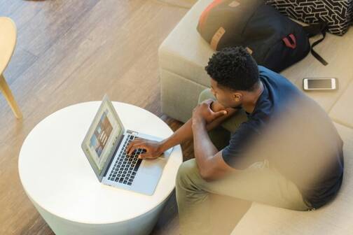 Mann sitzt im Coworking mit MacBook