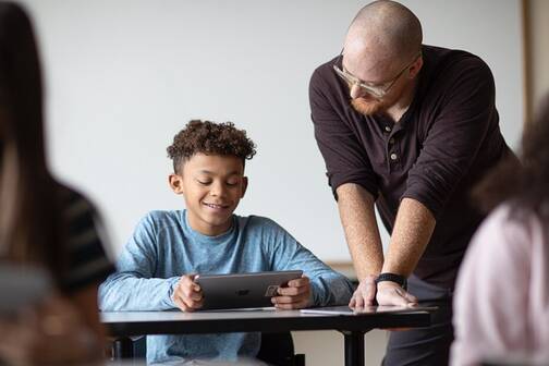 Lehrperson hilft Schüler mit iPad