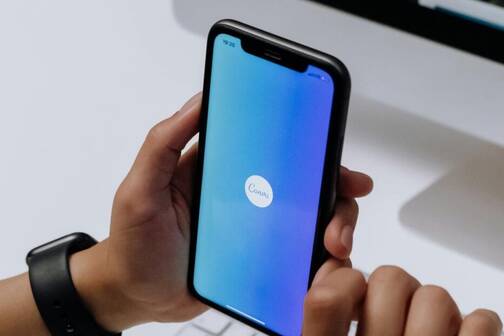 iPhone mit blauem Screen und Canva-App Logo
